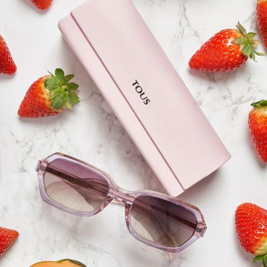 bodeg&oacute;n de uns &oacute;culos Tous com a sua bolsa e uns morangos em cima de uma bancada