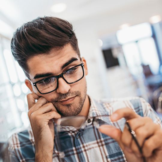 Homem m&iacute;ope a escolher &oacute;culos de corre&ccedil;&atilde;o