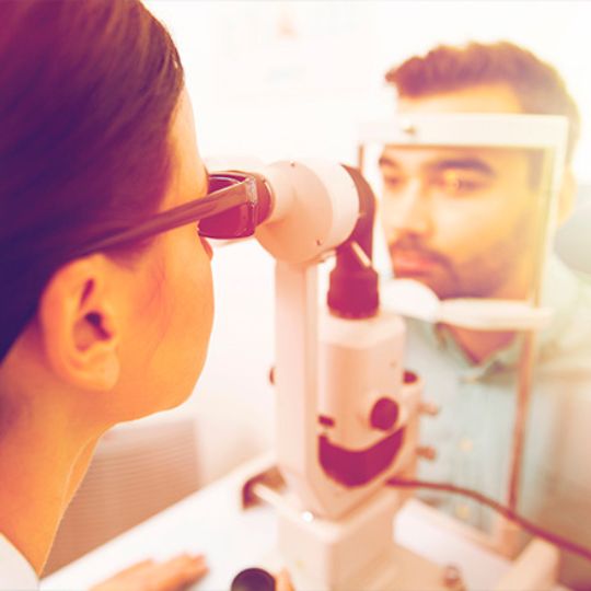 Óptico a realizar um exame ocular a um homem