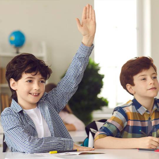 Criança numa sala de aula a levantar a mão
