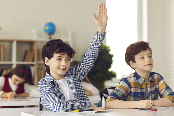 Criança numa sala de aula a levantar a mão