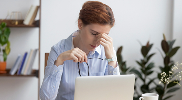 Mulher com hipermetropia a esfregar os olhos em frente ao computador
